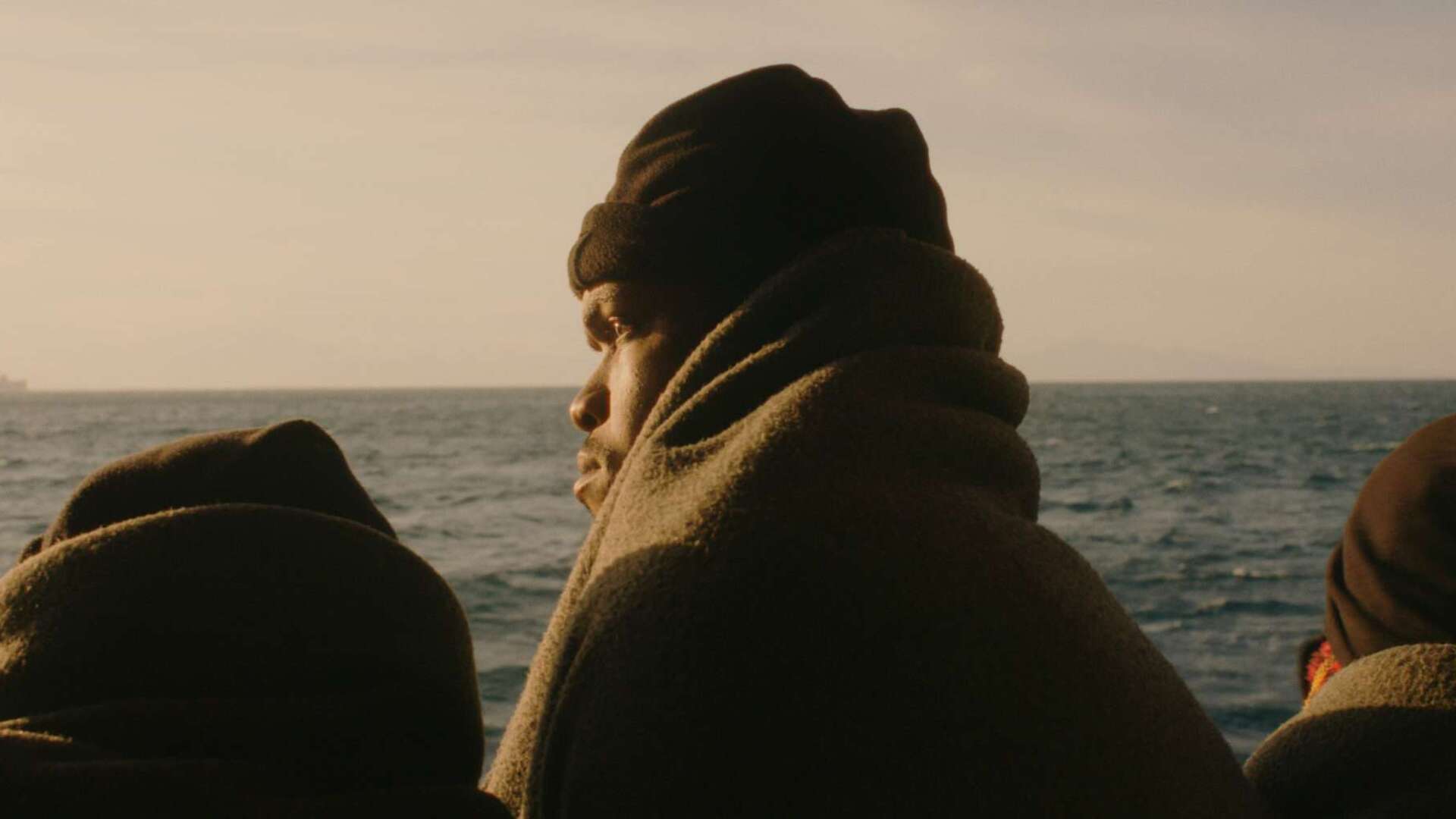 Eingehuellter Mann schaut auf Meer